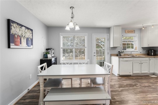 dining area featuring dark wood-style floors, a textured ceiling, a notable chandelier, and baseboards