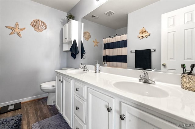 full bath featuring toilet, double vanity, a sink, and visible vents