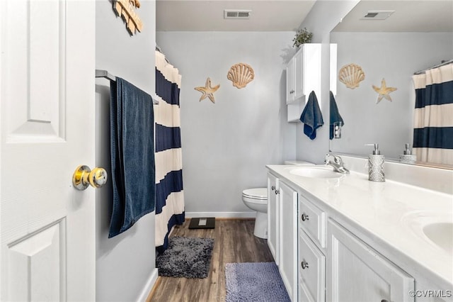 full bath with wood finished floors, visible vents, a sink, and double vanity