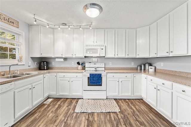 kitchen featuring dark wood-style flooring, light countertops, white cabinets, a sink, and white appliances