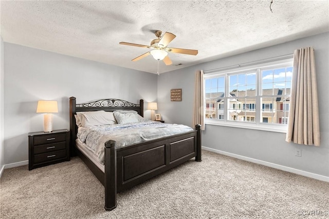 bedroom with light carpet, a textured ceiling, baseboards, and a ceiling fan