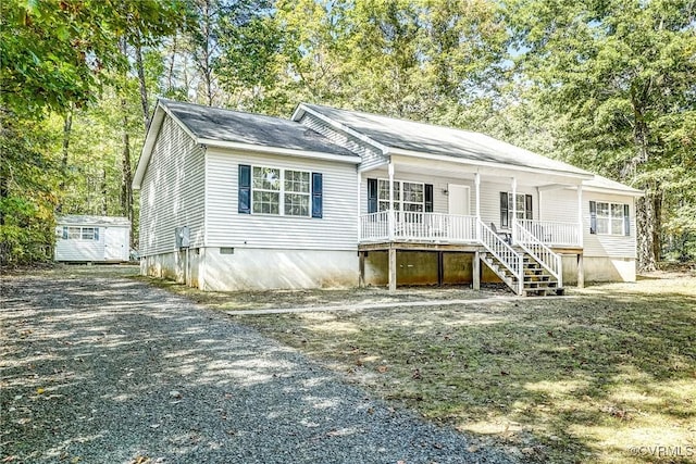 view of front of home with a storage shed, an outbuilding, gravel driveway, stairs, and a porch