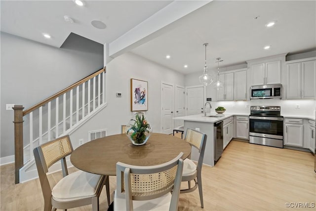 dining space featuring light wood finished floors, recessed lighting, visible vents, baseboards, and stairs