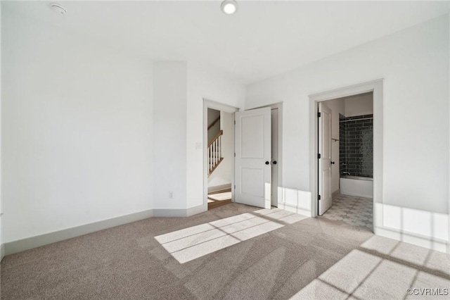 unfurnished bedroom featuring ensuite bath, baseboards, and light colored carpet