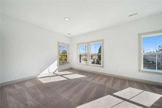 carpeted spare room with baseboards and visible vents