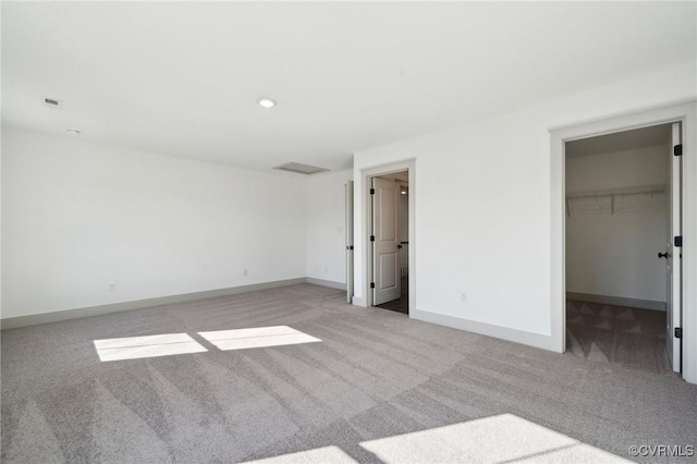 unfurnished bedroom with light carpet, a spacious closet, visible vents, and baseboards