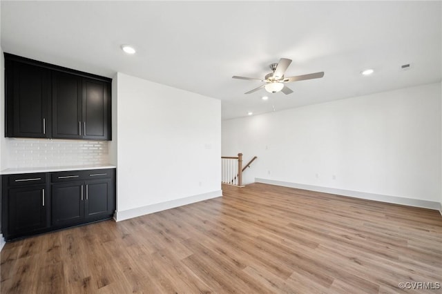 unfurnished living room with recessed lighting, visible vents, light wood-style flooring, a ceiling fan, and baseboards