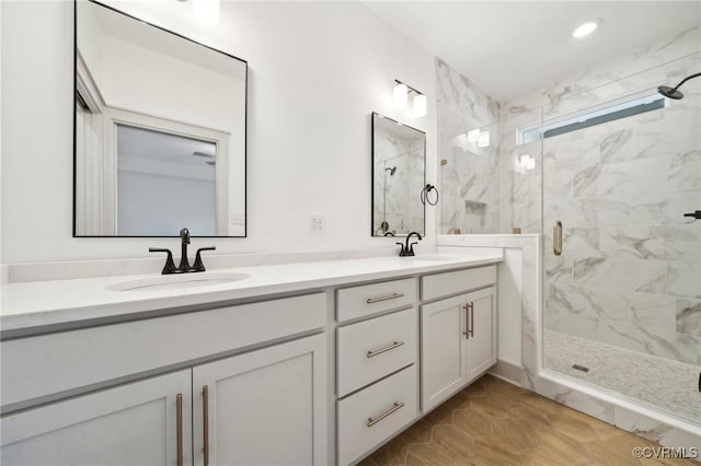 bathroom featuring a sink, a marble finish shower, and double vanity