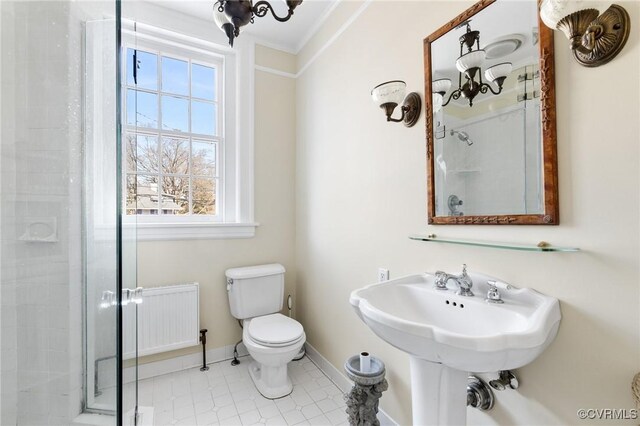 bathroom featuring radiator, toilet, ornamental molding, a stall shower, and baseboards