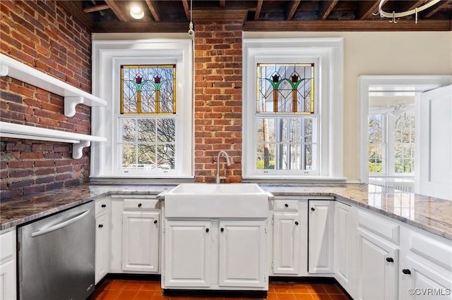 kitchen featuring a sink, a wealth of natural light, brick wall, and stainless steel dishwasher