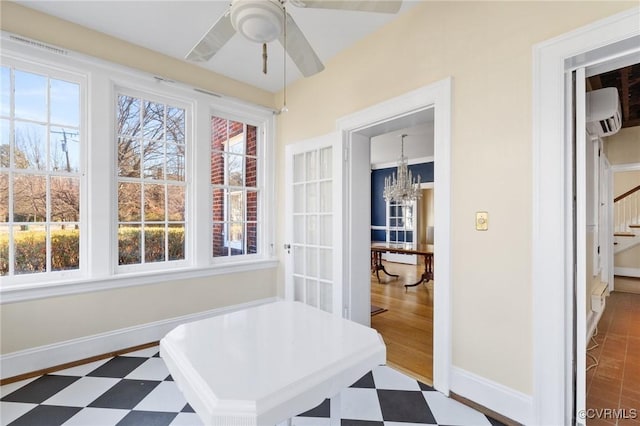 sunroom featuring ceiling fan with notable chandelier and a wall mounted air conditioner