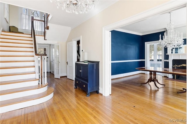 foyer with hardwood / wood-style floors, stairway, a notable chandelier, and ornamental molding