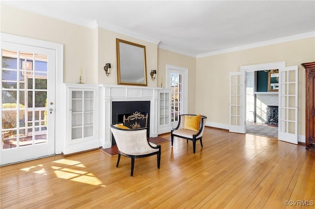 living area with french doors, hardwood / wood-style floors, a fireplace, and crown molding