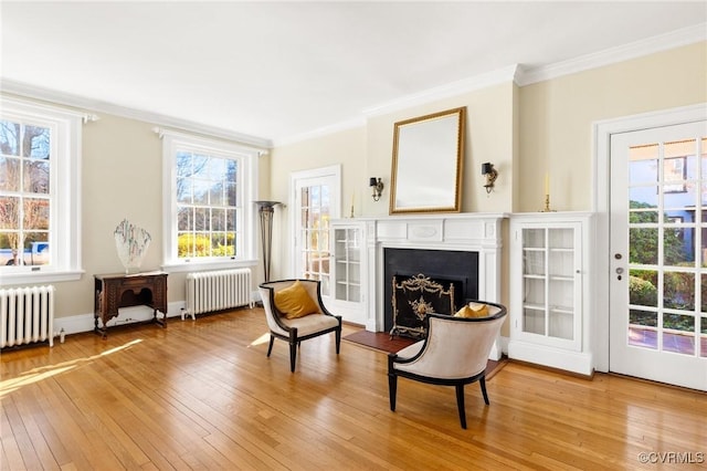 sitting room with crown molding, hardwood / wood-style floors, and radiator heating unit