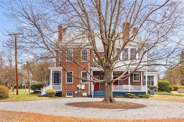 view of front of home with central AC, brick siding, a chimney, and a sunroom