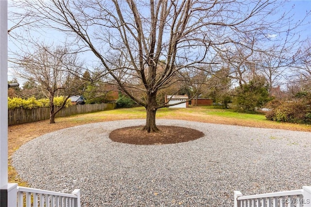 view of yard with curved driveway and fence