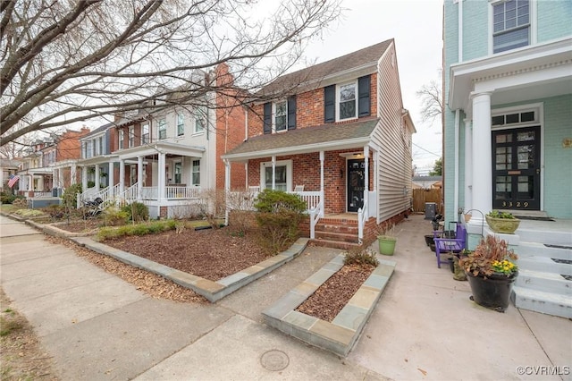 view of front of house with a residential view, covered porch, and brick siding