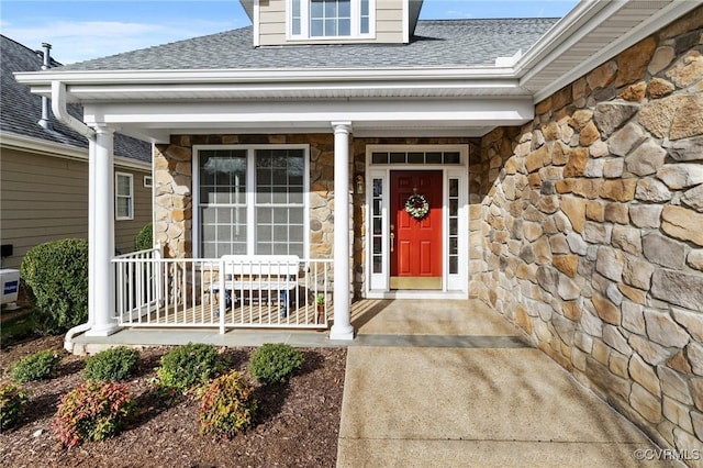 property entrance with stone siding, a shingled roof, and a porch