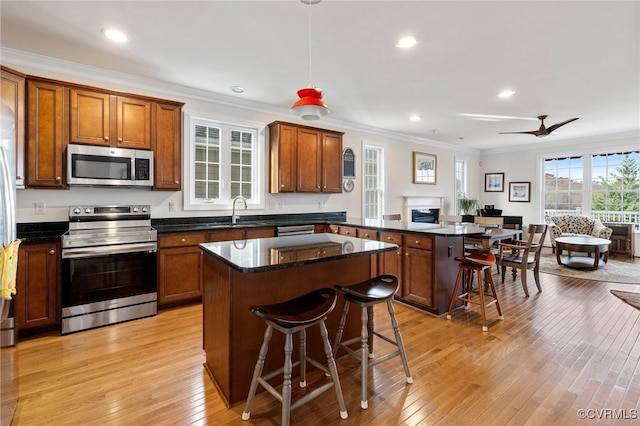 kitchen with hanging light fixtures, appliances with stainless steel finishes, a peninsula, and a kitchen breakfast bar