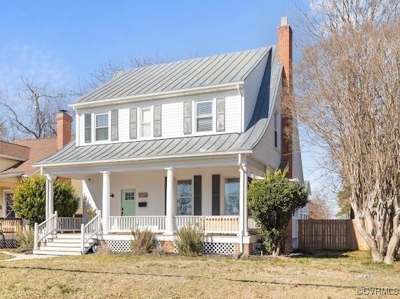 view of front of property with metal roof, a standing seam roof, a chimney, and a porch