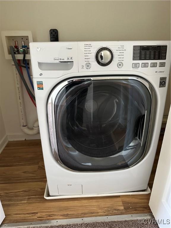 clothes washing area featuring wood finished floors and washer / dryer