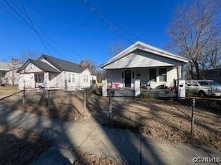 bungalow-style home featuring a porch and a fenced front yard