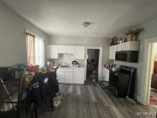 kitchen featuring range with electric stovetop, light countertops, dark wood-type flooring, white cabinets, and black microwave