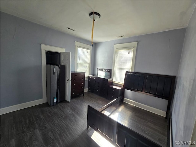 unfurnished bedroom with dark wood-style floors, visible vents, and baseboards