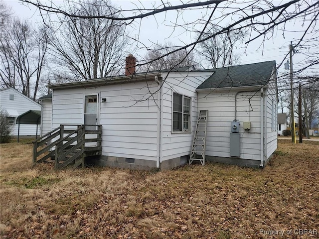 rear view of house featuring a shingled roof, crawl space, and a chimney