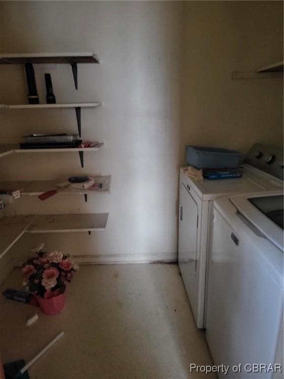 washroom featuring laundry area, baseboards, and washer and clothes dryer