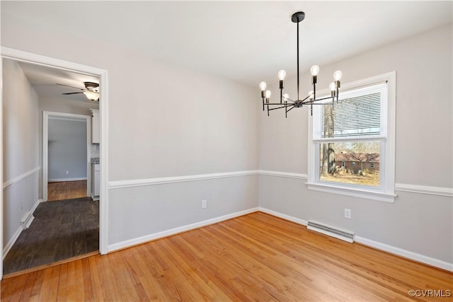 interior space featuring ceiling fan with notable chandelier, visible vents, baseboards, and wood finished floors