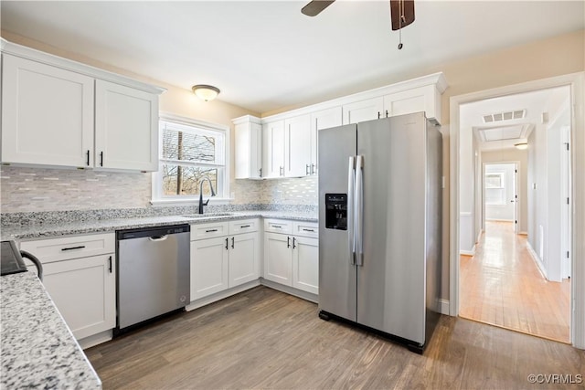 kitchen featuring visible vents, appliances with stainless steel finishes, white cabinetry, a sink, and wood finished floors