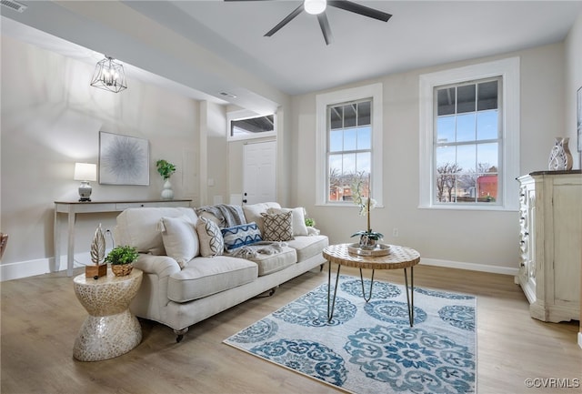 living area featuring a ceiling fan, light wood-style flooring, and baseboards