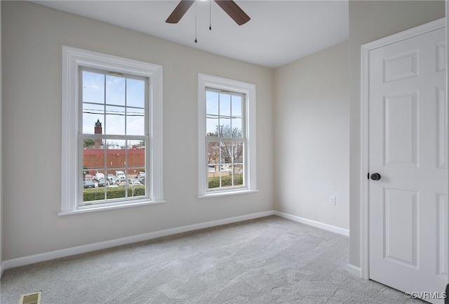 empty room featuring ceiling fan, carpet floors, visible vents, and baseboards