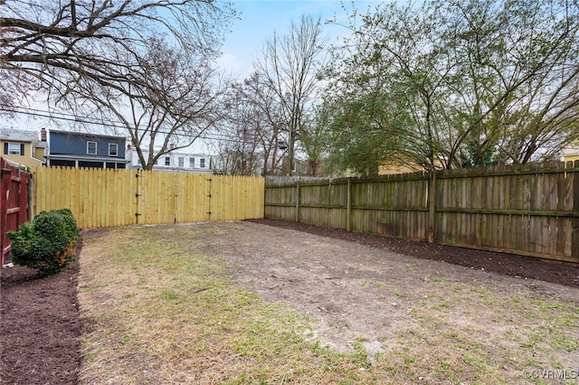 view of yard with a fenced backyard and a gate