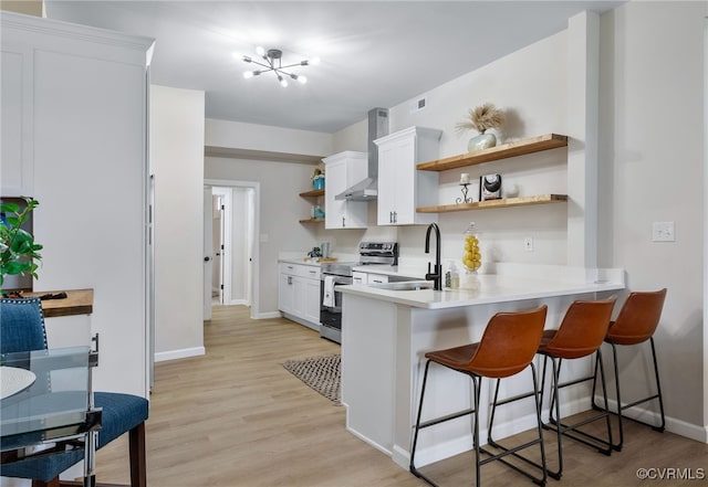 kitchen with light wood finished floors, electric range, light countertops, open shelves, and a sink