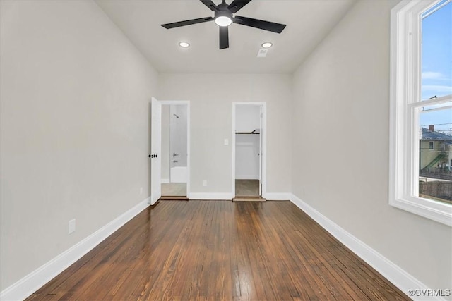 unfurnished bedroom featuring baseboards, dark wood-style floors, a spacious closet, a closet, and recessed lighting