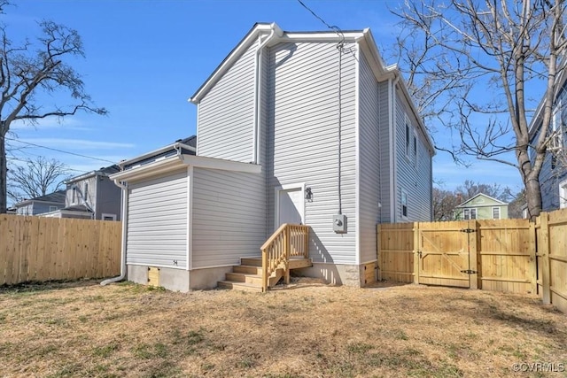 rear view of property featuring a yard, a gate, and fence