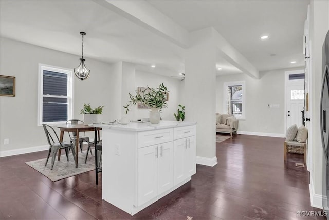 kitchen with dark wood-style floors, white cabinets, hanging light fixtures, and baseboards