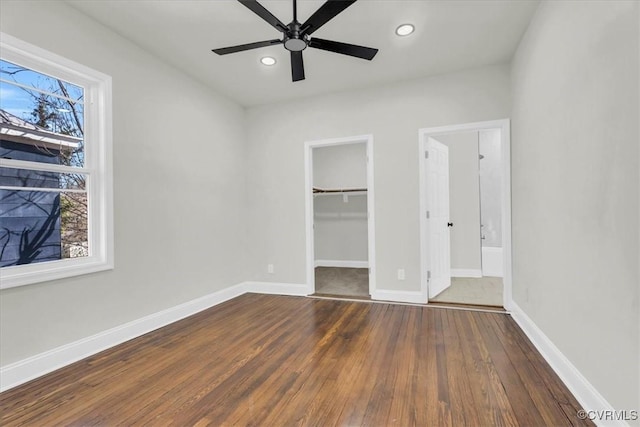 unfurnished bedroom with dark wood-style floors, multiple windows, and baseboards