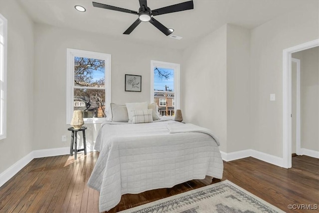 bedroom featuring multiple windows, baseboards, and wood finished floors