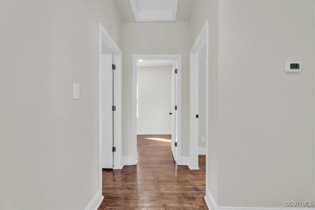 hall with dark wood-type flooring and baseboards