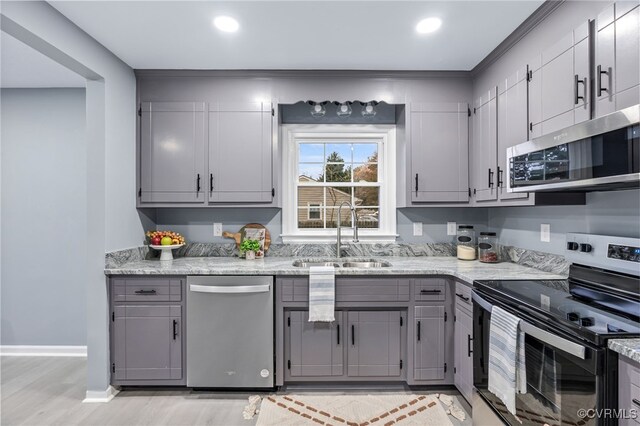 kitchen featuring gray cabinets, baseboards, stainless steel appliances, and a sink