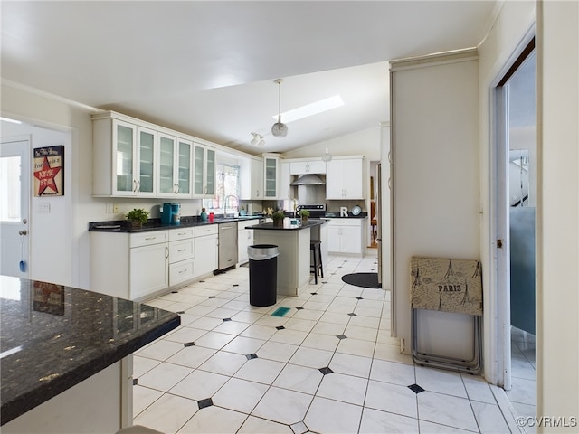 kitchen featuring glass insert cabinets, a kitchen island, white cabinets, dark countertops, and decorative light fixtures