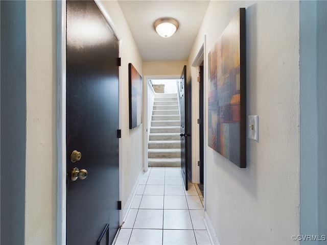 corridor with stairs, baseboards, and light tile patterned floors