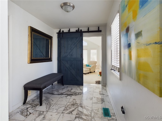 corridor featuring marble finish floor, visible vents, baseboards, and a barn door