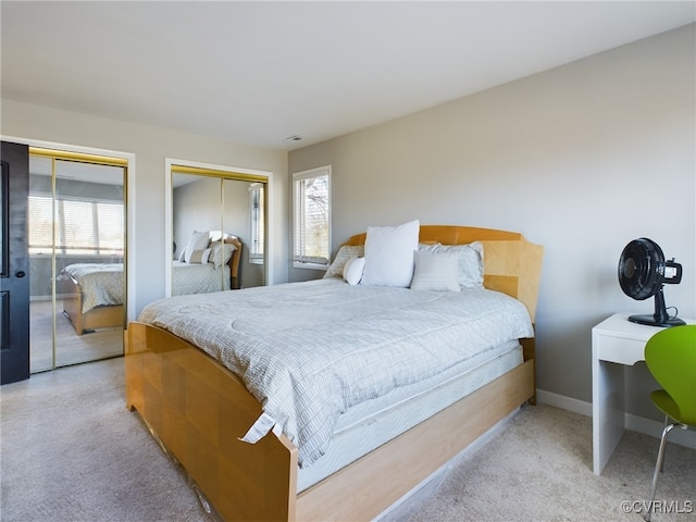 bedroom featuring multiple windows, two closets, and light colored carpet