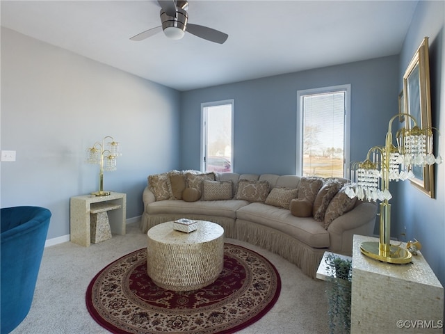 living area featuring light colored carpet, ceiling fan, and baseboards