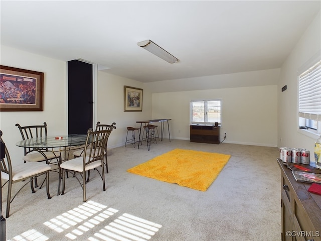 dining space featuring light carpet and baseboards