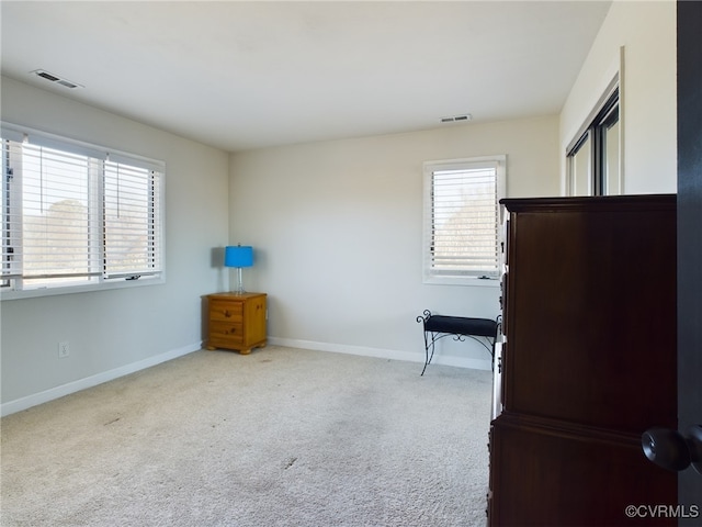 unfurnished bedroom featuring visible vents, light carpet, and baseboards